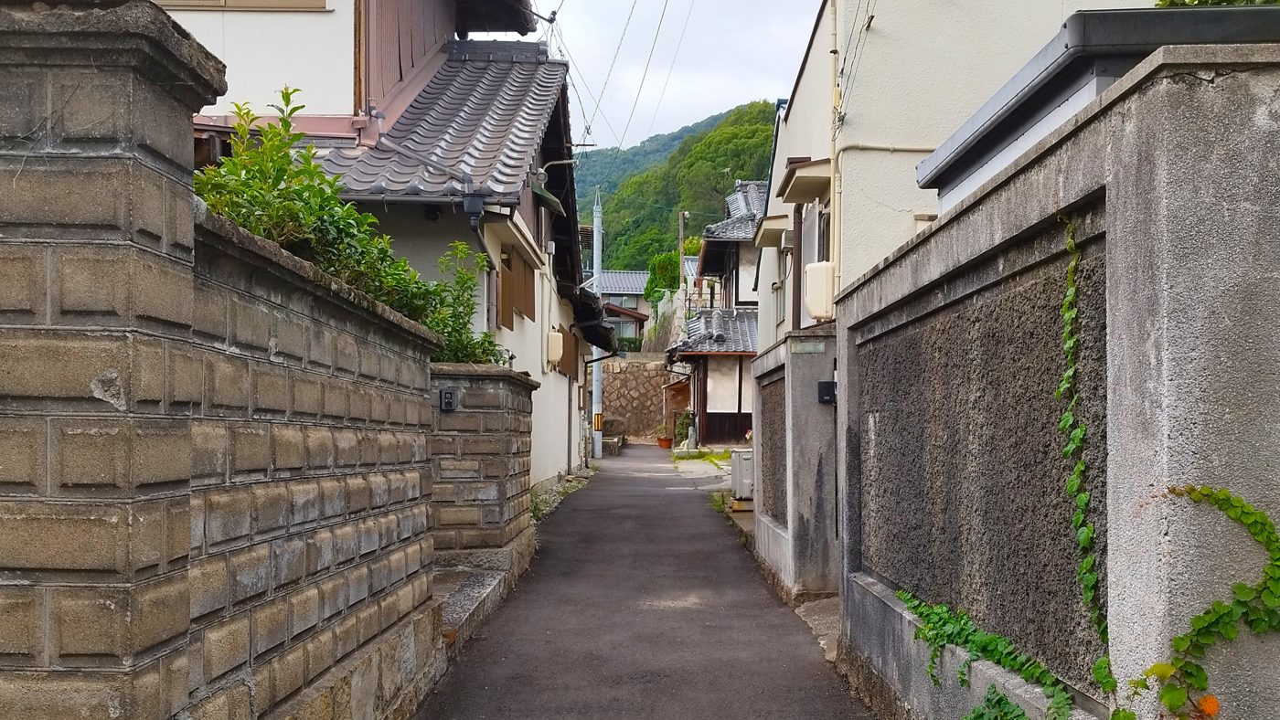石垣と古い家に挟まれた坂道の路地