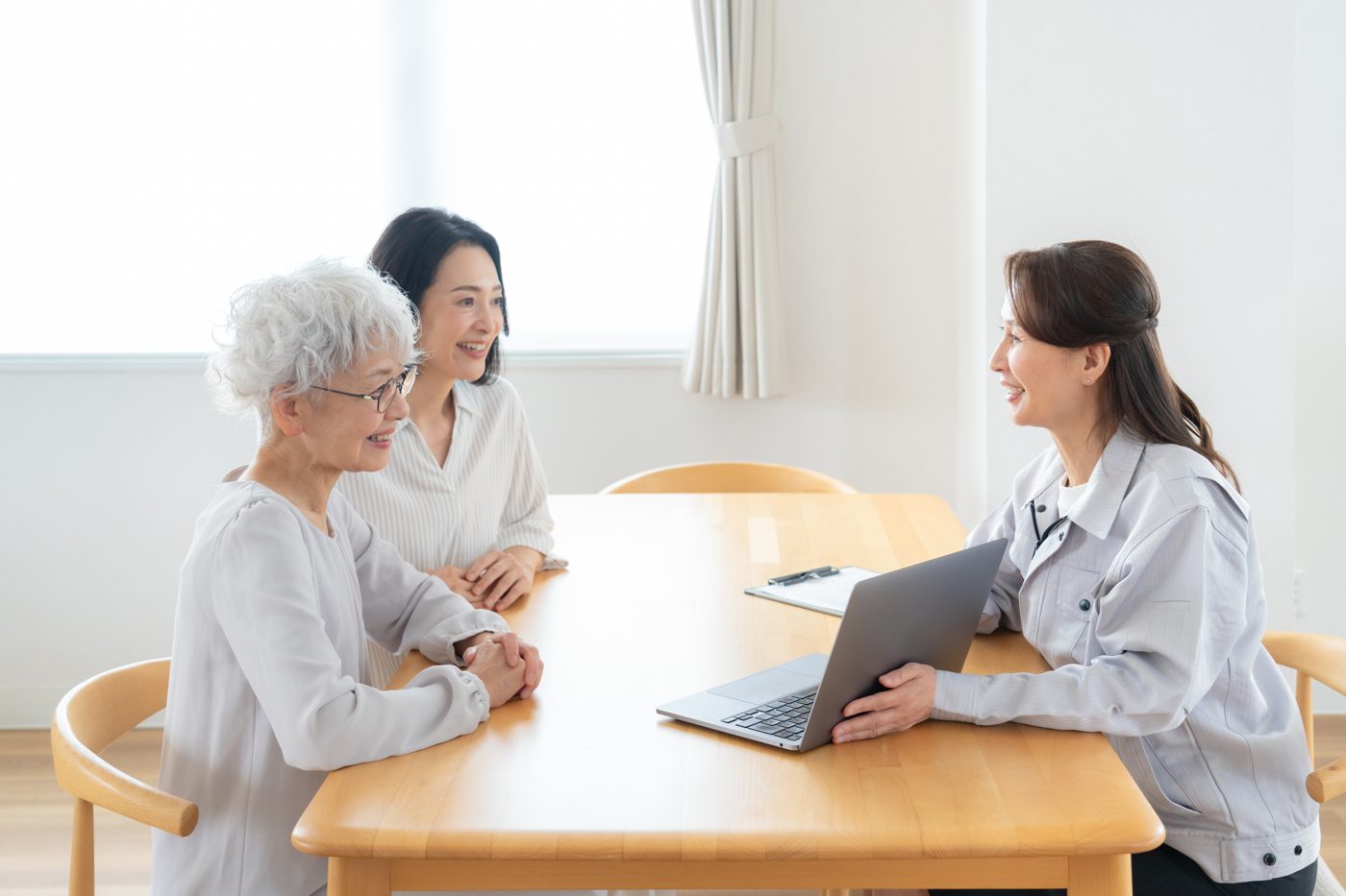 テーブルを囲んで話す高齢の女性と家族・担当者