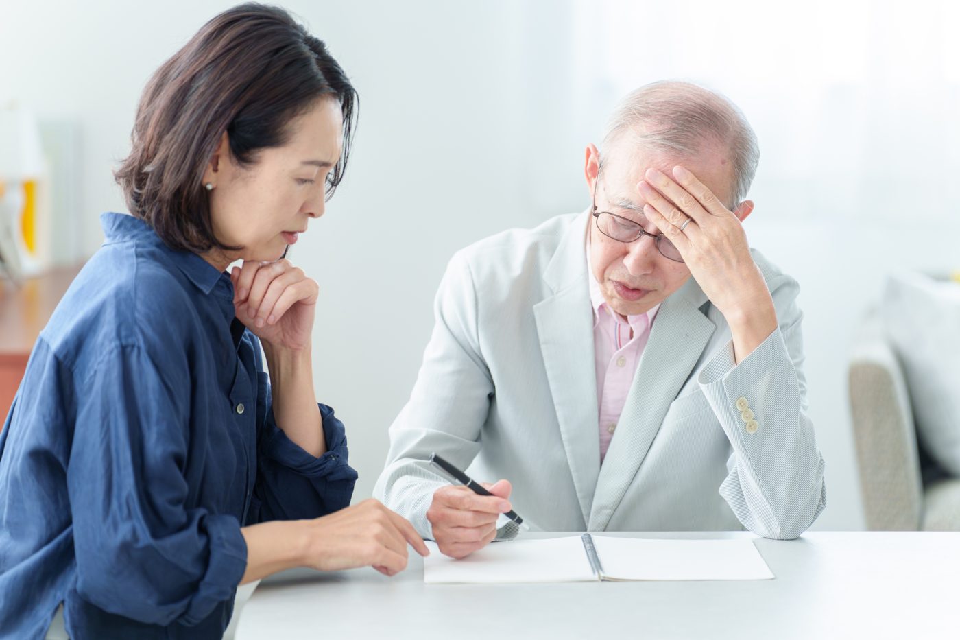 高齢の父親と娘が相続の書類を前に考え込んでいる様子